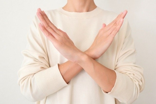 胸の前で、腕でバツを作る女性