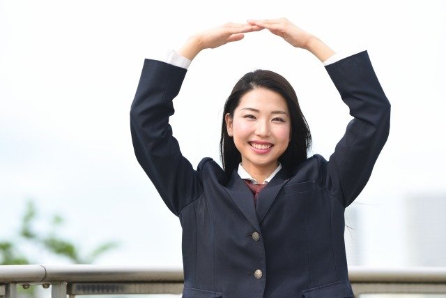 腕で丸を作っている女子高生