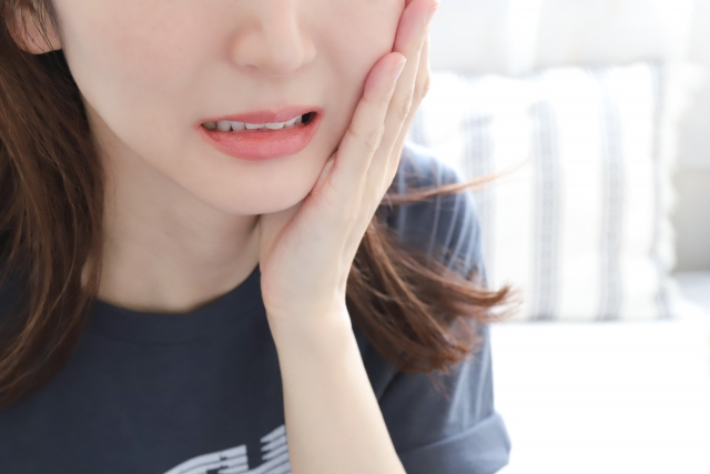 頬を手で押さえて痛そうにしている女性
