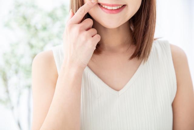 鏡で口元を見ている女性